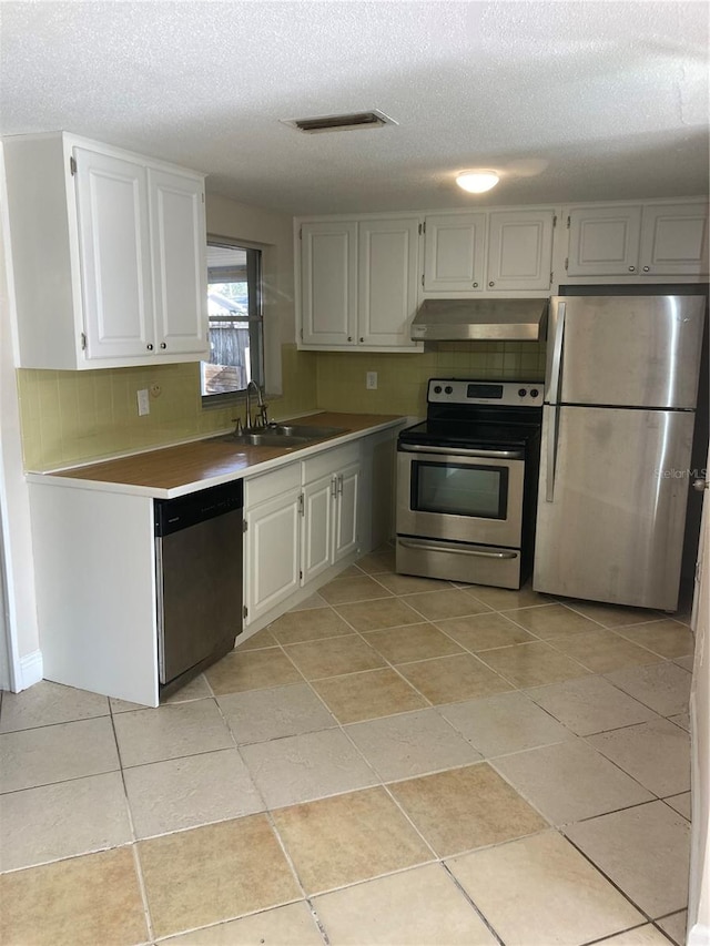 kitchen with appliances with stainless steel finishes, a textured ceiling, white cabinetry, and sink