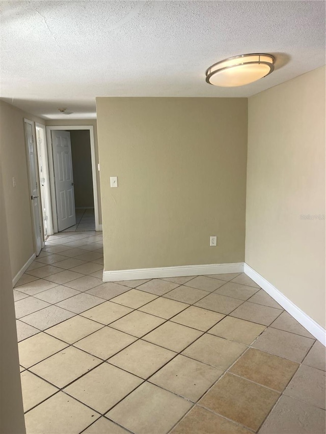 tiled empty room featuring a textured ceiling