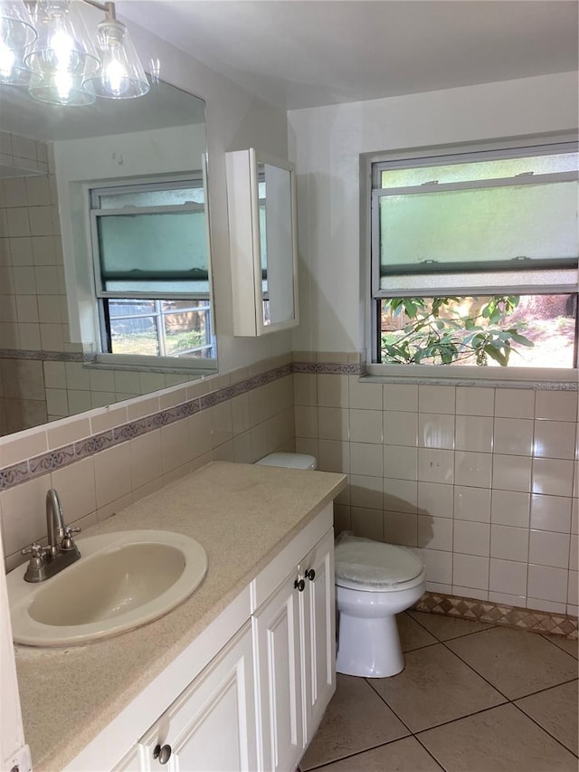 bathroom featuring tile patterned flooring, a healthy amount of sunlight, tile walls, and toilet