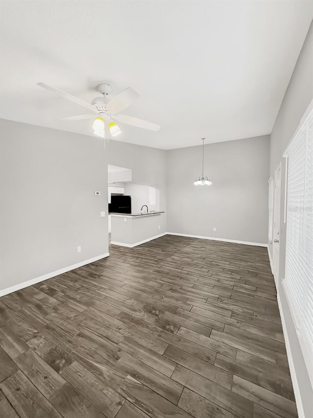 unfurnished living room with dark wood-type flooring and ceiling fan with notable chandelier