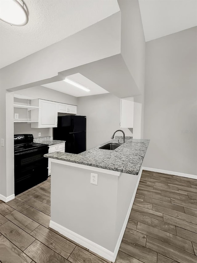 kitchen with light stone countertops, white cabinetry, sink, kitchen peninsula, and black appliances