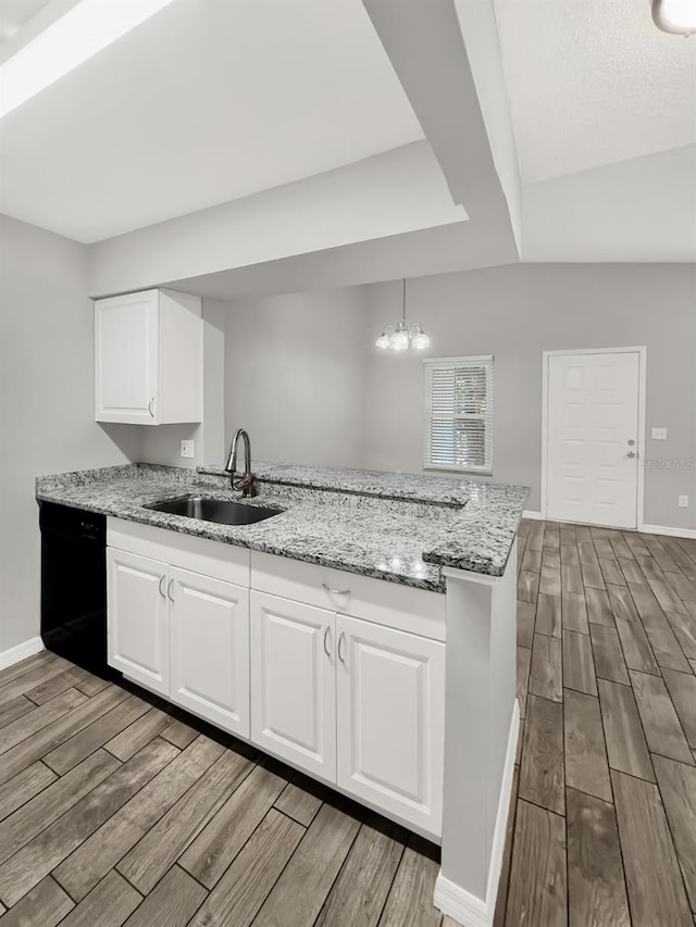 kitchen with light stone countertops, sink, white cabinetry, and kitchen peninsula