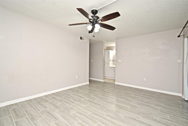 unfurnished room featuring a textured ceiling, ceiling fan, and light wood-type flooring