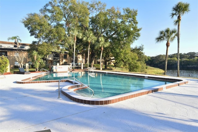 view of pool featuring a patio and a water view