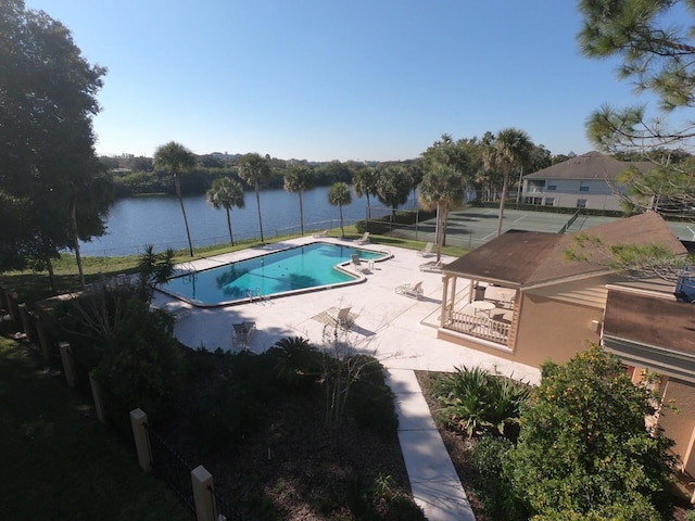 view of swimming pool featuring tennis court, a patio, and a water view