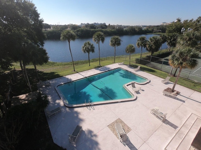 view of swimming pool featuring a patio, a water view, and a yard