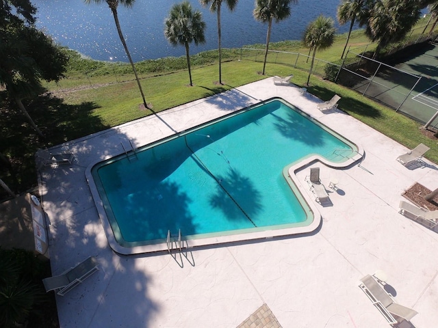 view of swimming pool featuring a patio area, a lawn, and a water view