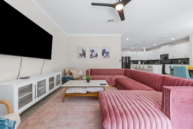 living room with sink, ceiling fan, and crown molding