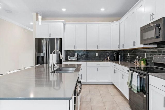 kitchen featuring appliances with stainless steel finishes, white cabinetry, decorative light fixtures, and sink