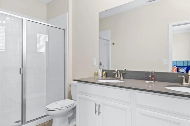 bathroom featuring toilet, vanity, and a shower with shower door