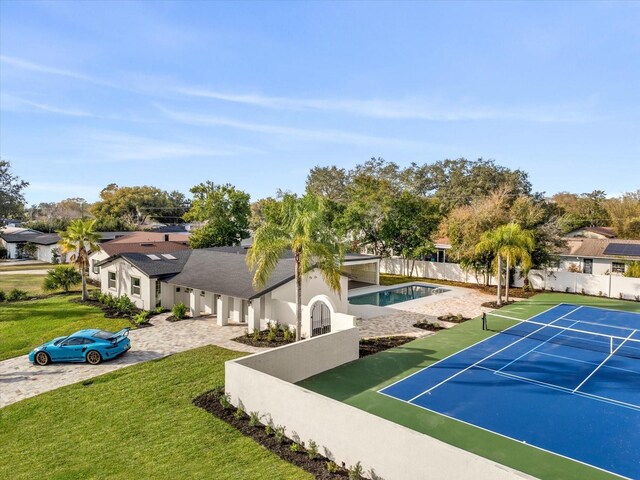 view of tennis court with a lawn and fence