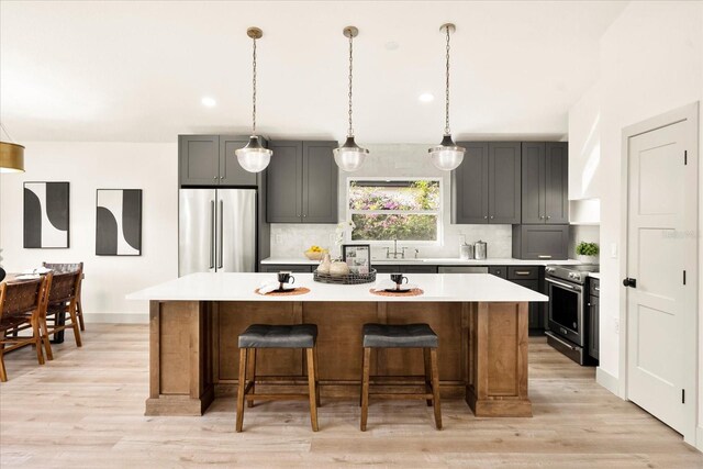 kitchen with a center island, light countertops, gray cabinetry, and high quality appliances