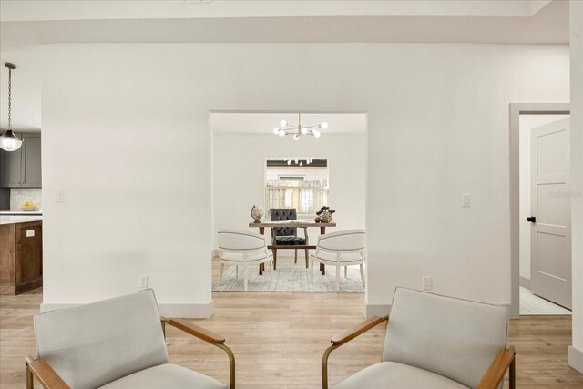 sitting room featuring light wood-style flooring, baseboards, and an inviting chandelier