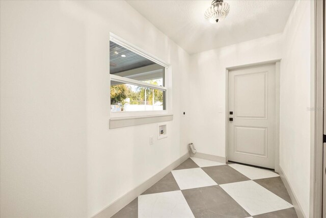 clothes washing area with light floors, baseboards, hookup for a washing machine, and laundry area