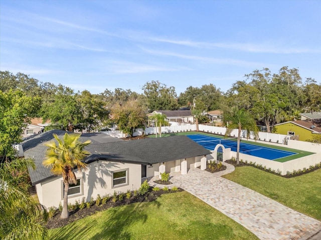 view of swimming pool with a tennis court, fence, and a yard