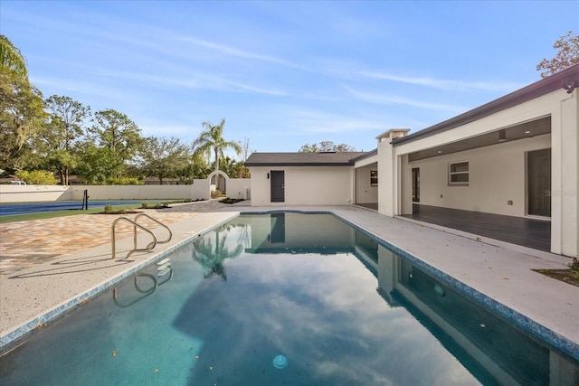 view of swimming pool featuring a patio, fence, and a storage unit