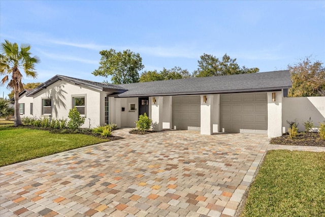 view of front of property featuring stucco siding, an attached garage, decorative driveway, and a front lawn