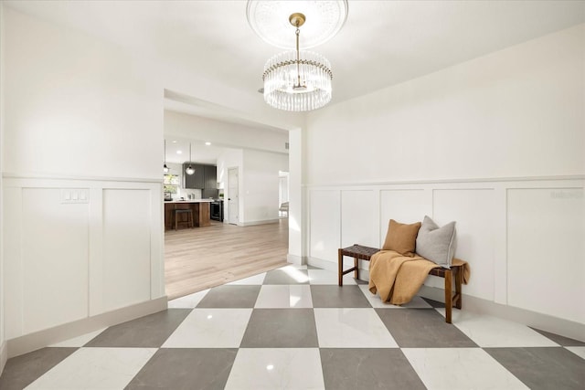 sitting room featuring a decorative wall, a chandelier, and wainscoting