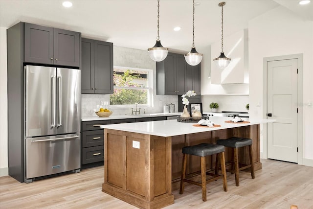 kitchen with high quality fridge, a center island, light wood-style floors, tasteful backsplash, and recessed lighting
