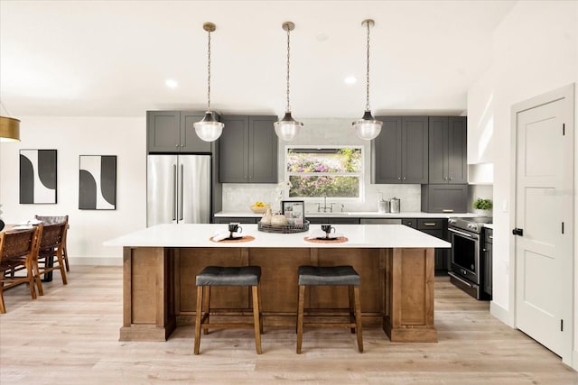 kitchen featuring stainless steel appliances, a center island, backsplash, light countertops, and light wood-type flooring