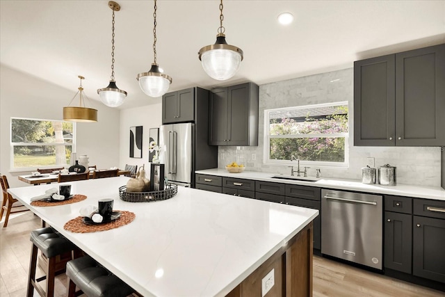 kitchen featuring appliances with stainless steel finishes, a sink, plenty of natural light, backsplash, and recessed lighting