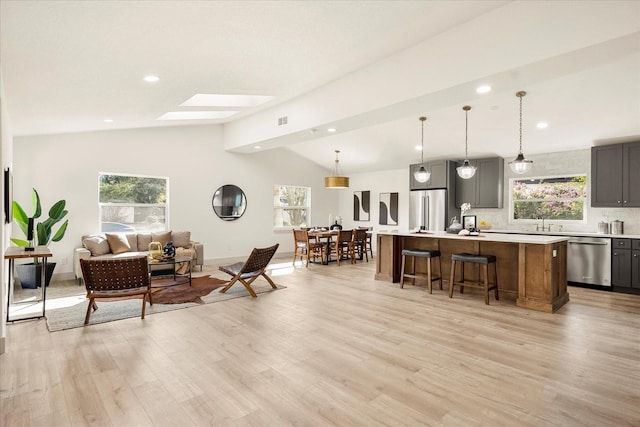 living room with vaulted ceiling, a skylight, light wood-style floors, and recessed lighting