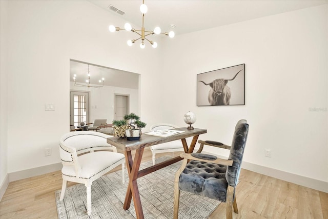 dining area with a chandelier, light wood finished floors, baseboards, and lofted ceiling