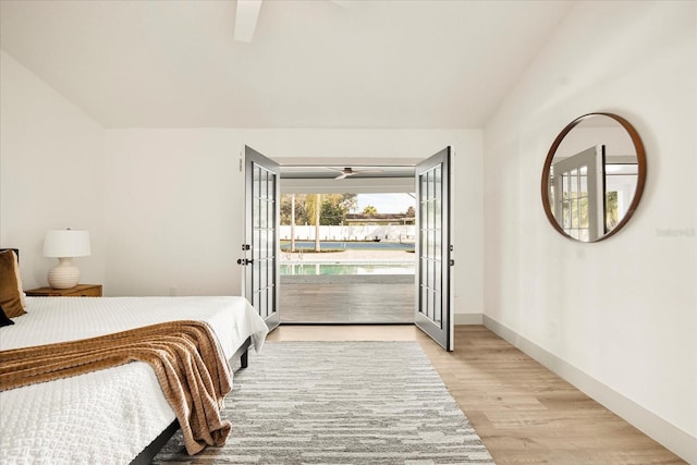 bedroom with access to outside, light wood-style flooring, lofted ceiling, a ceiling fan, and baseboards