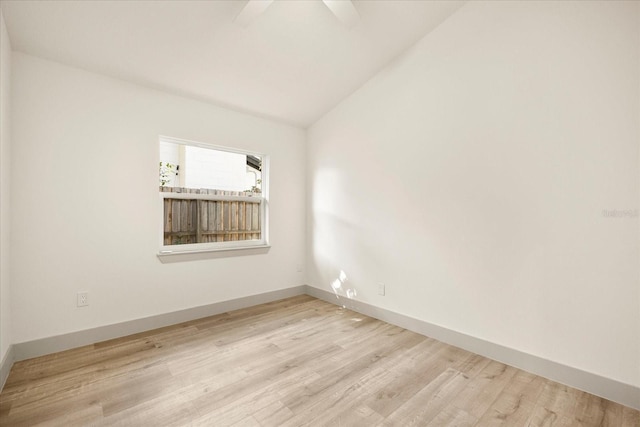 empty room with wood finished floors, vaulted ceiling, ceiling fan, and baseboards