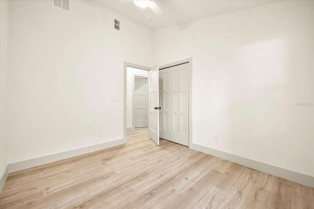empty room featuring light wood-type flooring, baseboards, and a ceiling fan