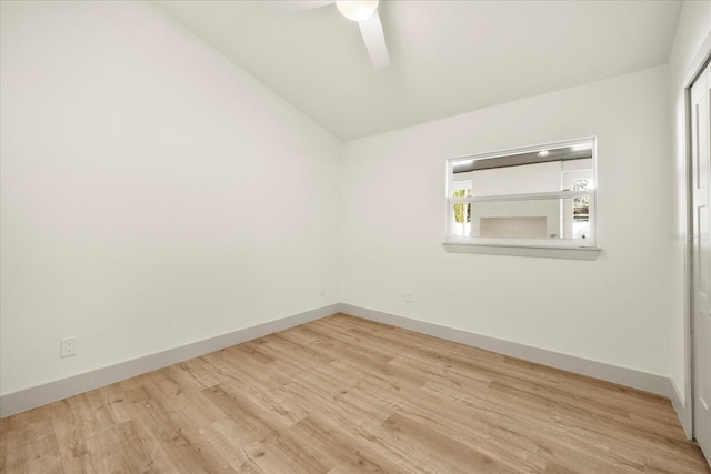 spare room featuring wood finished floors, ceiling fan, vaulted ceiling, and baseboards