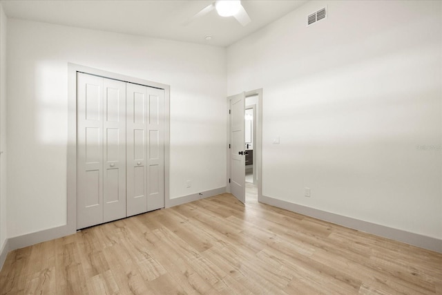 unfurnished bedroom featuring light wood finished floors, a closet, baseboards, and a ceiling fan