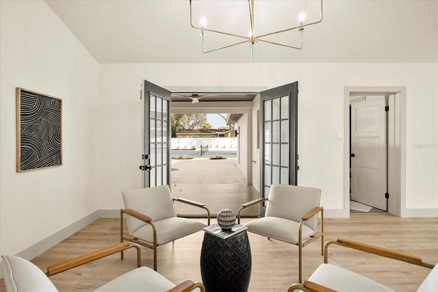 sitting room featuring wood finished floors, baseboards, french doors, and a chandelier