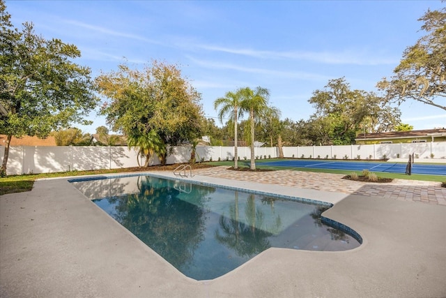 view of pool with fence and a tennis court