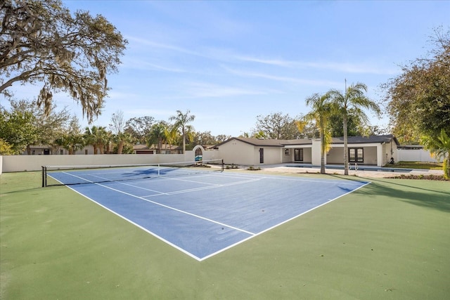 view of tennis court with community basketball court and fence