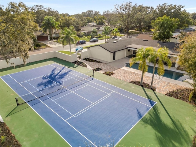 view of tennis court featuring fence and a residential view