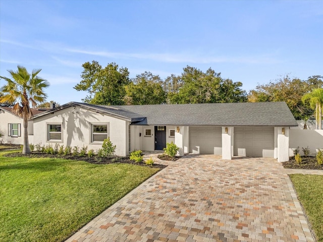 ranch-style home featuring an attached garage, decorative driveway, a front yard, and stucco siding