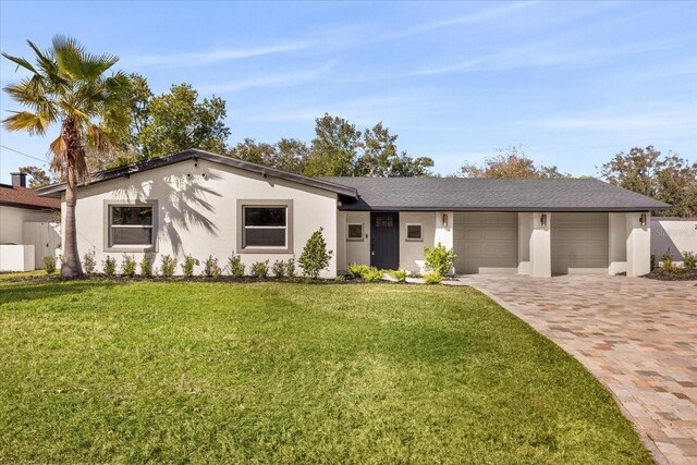 view of front of property with an attached garage, a front yard, driveway, and stucco siding