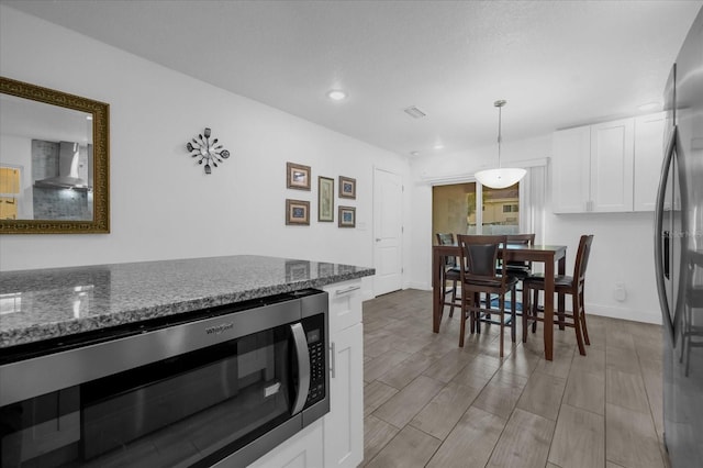 kitchen featuring white cabinets, pendant lighting, dark stone countertops, and stainless steel appliances