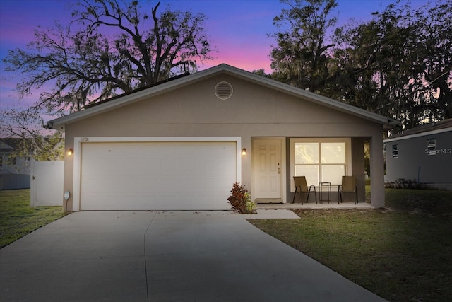 view of front of property featuring stucco siding, a front yard, an attached garage, and driveway