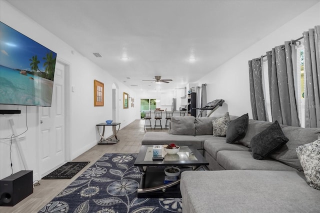 living room featuring light wood-type flooring, visible vents, and ceiling fan