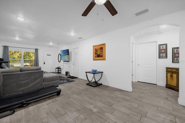 exercise room with visible vents, baseboards, wood finish floors, arched walkways, and a ceiling fan