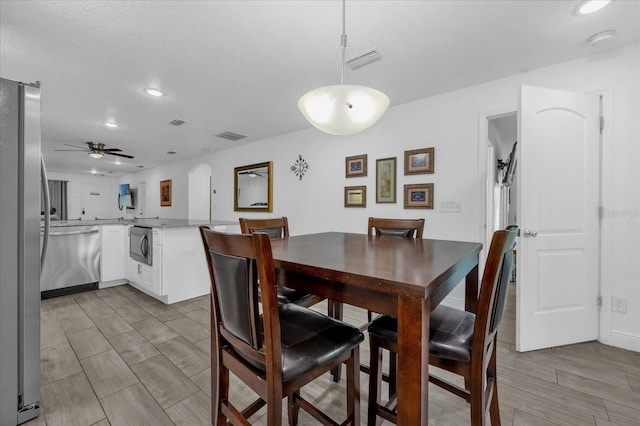 dining room featuring arched walkways, visible vents, wood finish floors, and ceiling fan