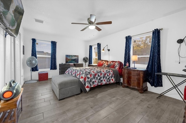 bedroom featuring visible vents, multiple windows, ceiling fan, and wood tiled floor