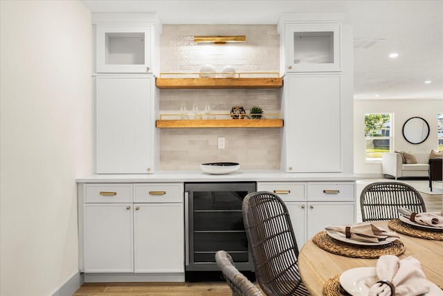 bar featuring wine cooler, backsplash, light hardwood / wood-style floors, and white cabinets