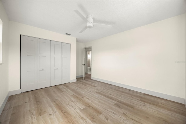 unfurnished bedroom featuring ceiling fan, a textured ceiling, a closet, and light wood-type flooring