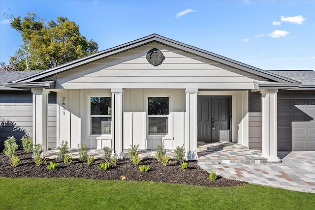 view of front of home with board and batten siding, a shingled roof, a front lawn, and a garage