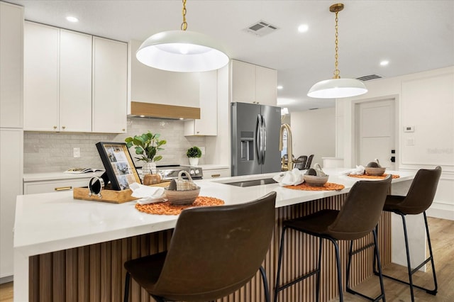 kitchen with white cabinets, stainless steel fridge with ice dispenser, light countertops, backsplash, and visible vents