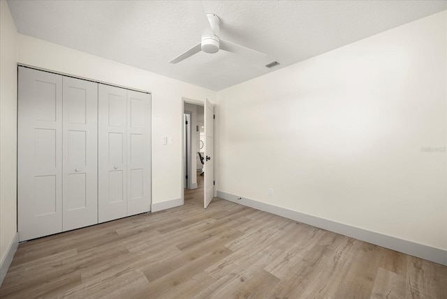 unfurnished bedroom with ceiling fan, light wood-style flooring, baseboards, visible vents, and a closet