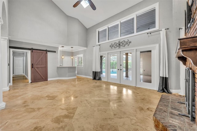 unfurnished living room featuring ceiling fan, a barn door, high vaulted ceiling, and french doors